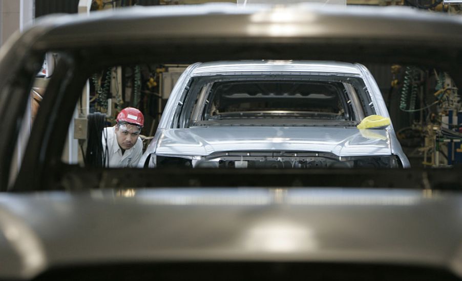 Workers assemble Toyota trucks in a factory