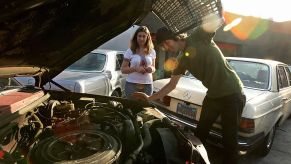 A man looking over his car, getting ready to change his oil during regular maintenance