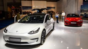 Tesla Model 3 compact sedan car in white with a Tesla Model S dual motor all electric sedan on display at Brussels Expo