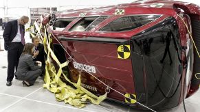 Workers examine an SUV after a crash test