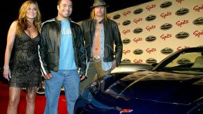 Carmen Electra, Joe Rogan, and Kid Rock standing next to a sports car