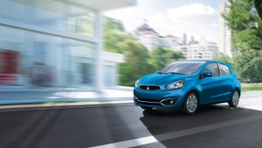 A blue 2020 Mitsubishi Mirage hatchback driving through a city.