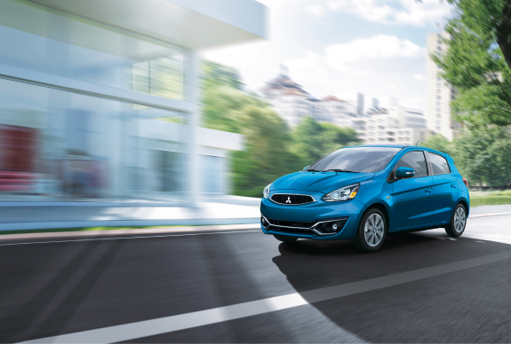 A blue 2020 Mitsubishi Mirage hatchback driving through a city.