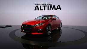 A red Nissan Altima on display at an auto show