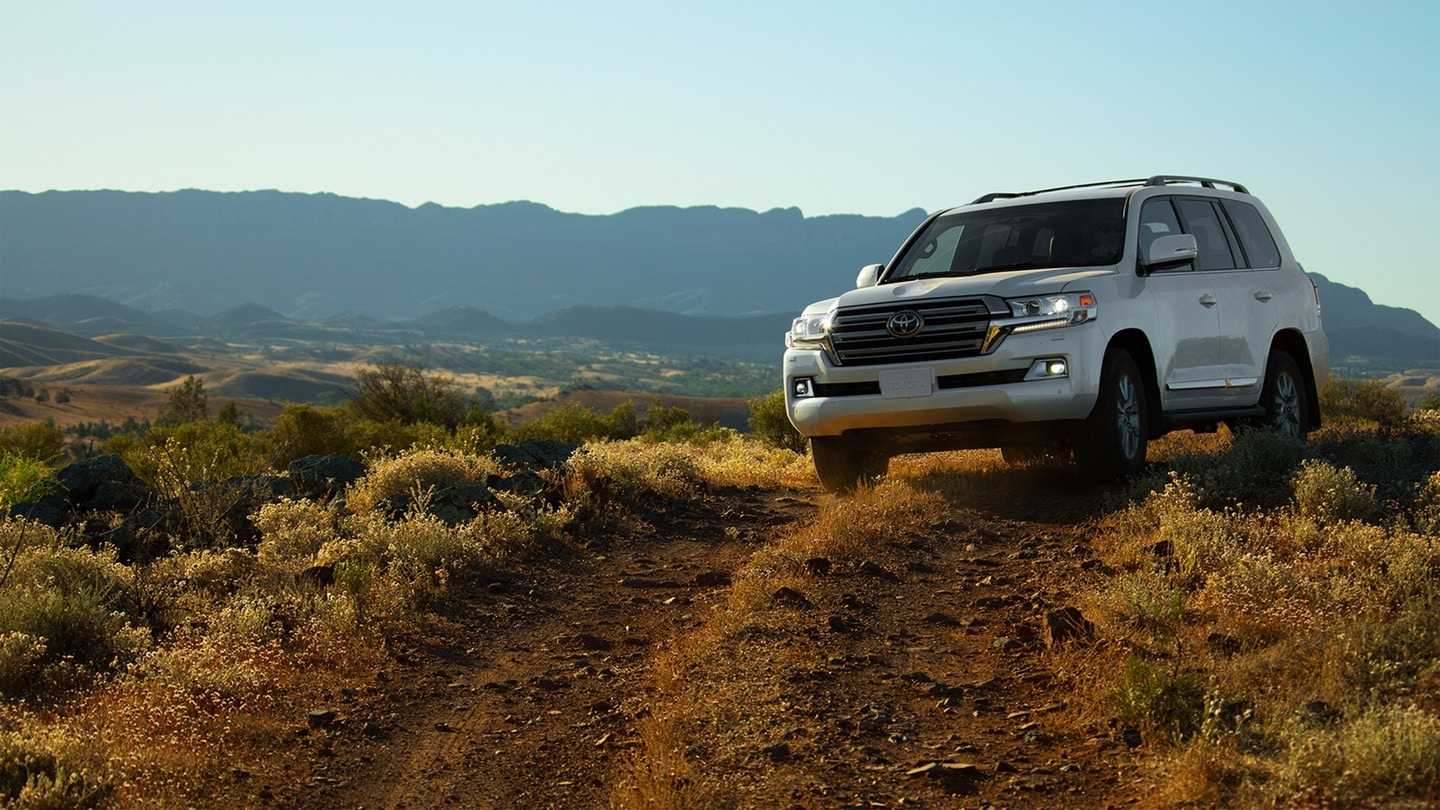 a white Toyota land cruiser driving off road on a mountain trail