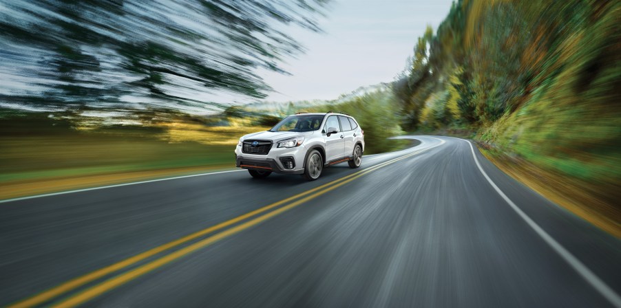 a white subaru forester crossover SUV at speed on a scenic road