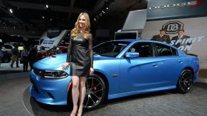 A model posing with a Dodge Charger at an auto show