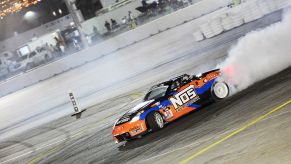 A blue and orange Nissan 350Z with a large white NOS decal drifts around a corner at the Las VEgas Motor Speedway