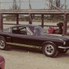 Black-with-gold-stripes 1966 Ford Shelby GT350H Mustang, parked with radio antenna extended