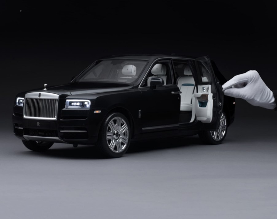 Black 1:8-scale Rolls-Royce Cullinan model with white-gloved hand for scale