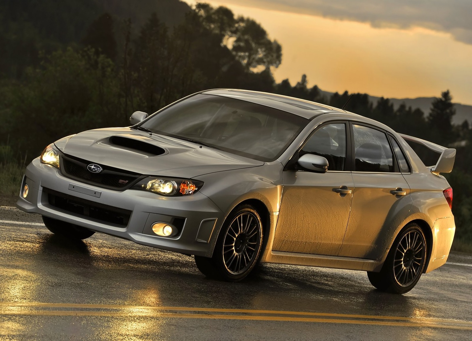 A silver 2011 Subaru Impreza WRX STI driving on a wet road