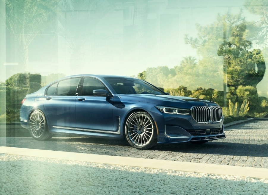 Dark blue 2020 Alpina B7 behind glass, with trees reflecting on the glass