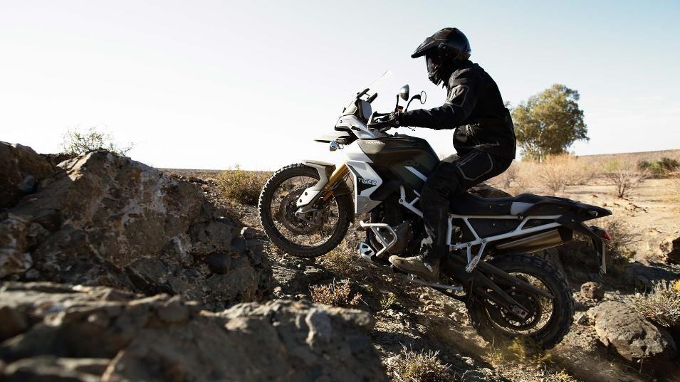 White-and-black 2020 Triumph Tiger 900 Rally Pro scrambling over rocks in the desert