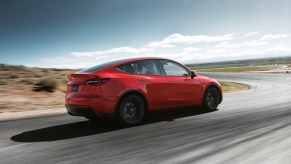 Red 2021 Tesla Model Y rear view, while it drives on a curvy road