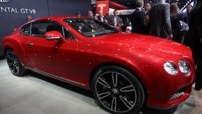 A red Bentley Continental GT sits on stage at a car show