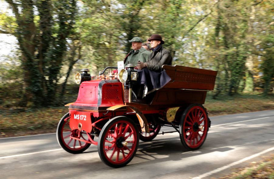 Two men riding an old car