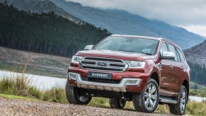 A Red Ford Everest on the banks of a river in a valley