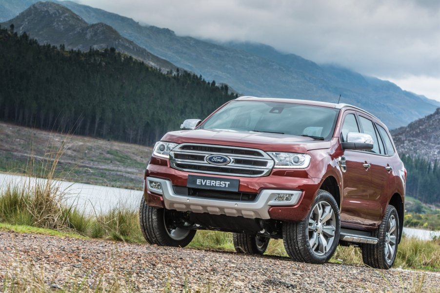 A Red Ford Everest on the banks of a river in a valley