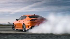 An orange Kia Stinger GTS performs a burnout