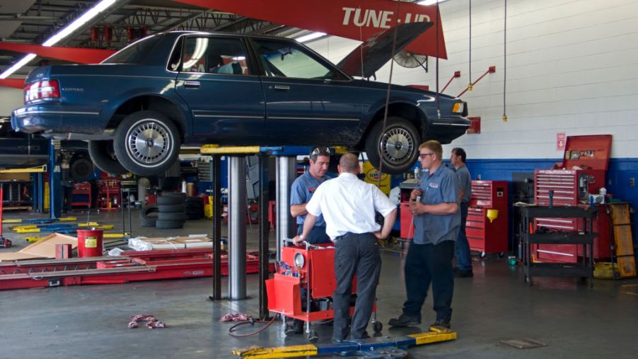 Motor car on hydraulic lift repair workshop