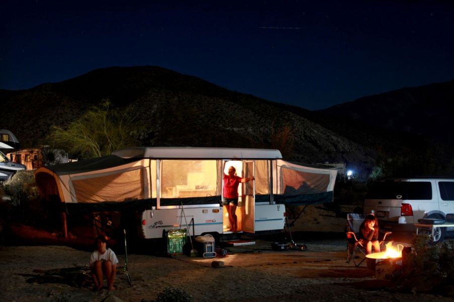 Pop-up camper set up in a campsite complete with a campfire