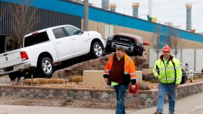 Workers leaving a factory with two Ram 1500 trucks in the background