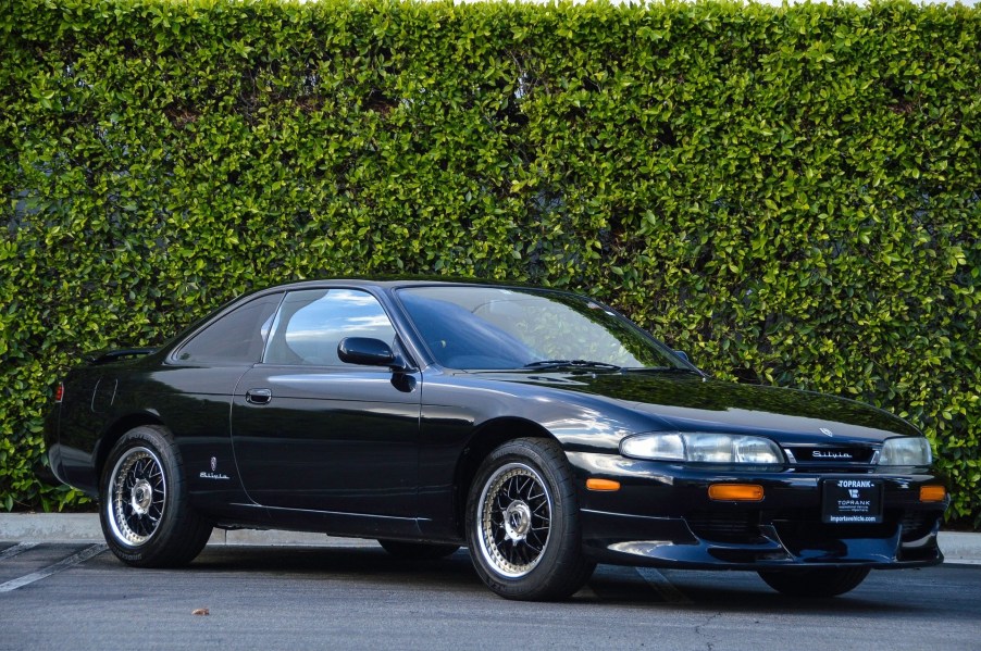 Black 1994 Nissan Silvia coupe in front of a hedge