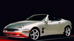 Silver 1999 Qvale Mangusta with the roof down against a black background