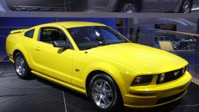 A yellow 2006 Ford Mustang on display at an auto show