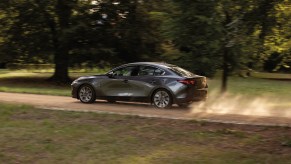 a gray Mazda3 Sedan in motion on a scenic dirt road