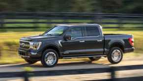 A black 2021 Ford F-150 rides on a dirt road.