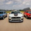 A white 2021 Mustang Mach I flanked by the original 1969 Mach Is in red and blue