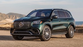 A green 2021 Mercedes-AMG GLS 63 parked overlooking a mountain-ringed beach