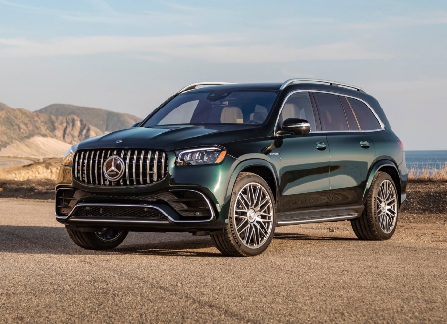 A green 2021 Mercedes-AMG GLS 63 parked overlooking a mountain-ringed beach