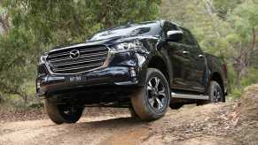 Black 2021 Mazda BT-50 pickup truck rising over a ridge