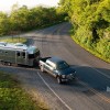 Silver Airstream Flying Cloud camper being towed by a blue Ford F-150 in a forested national park