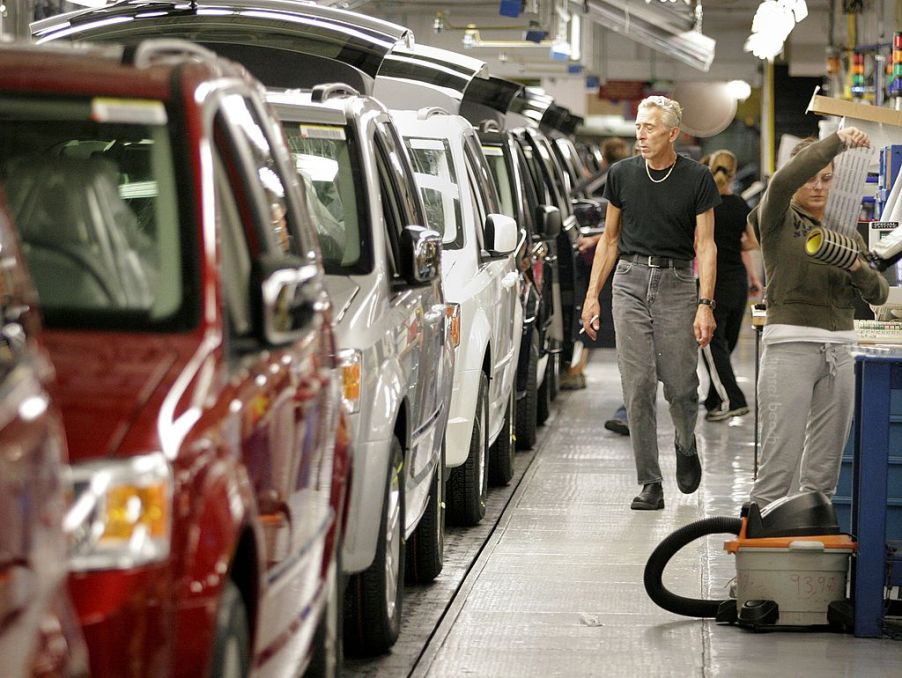 A man inspecting a row of minivans in a factory