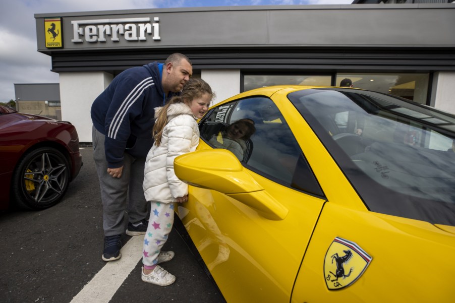 A father and his daughter looking at a new yellow Ferrari