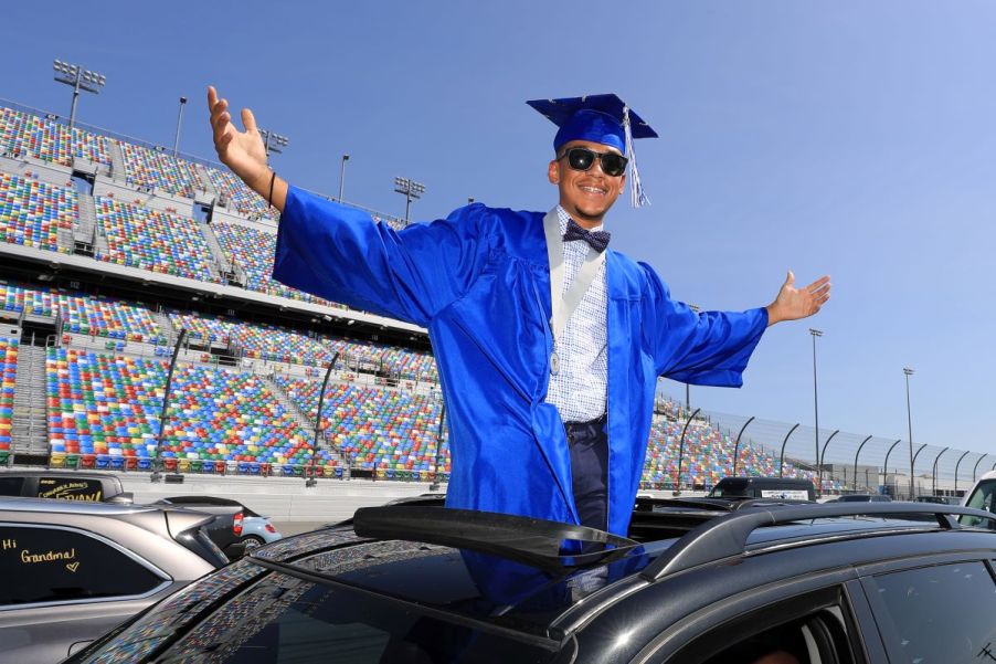 A high school senior in cap and gown arrives at his graduation at Daytona International Speedway