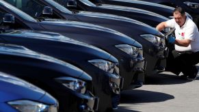 A worker cleans new cars at a dealership lot