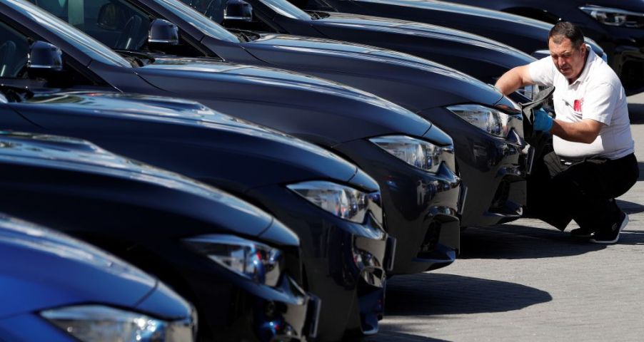 A worker cleans new cars at a dealership lot