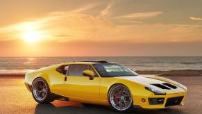 A yellow, custom, DeTomaso Pantera is parked before an ocean view.