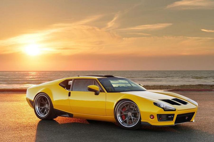 A yellow, custom, DeTomaso Pantera is parked before an ocean view.