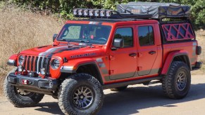 A red Jeep Gladiator parked on a dirt road