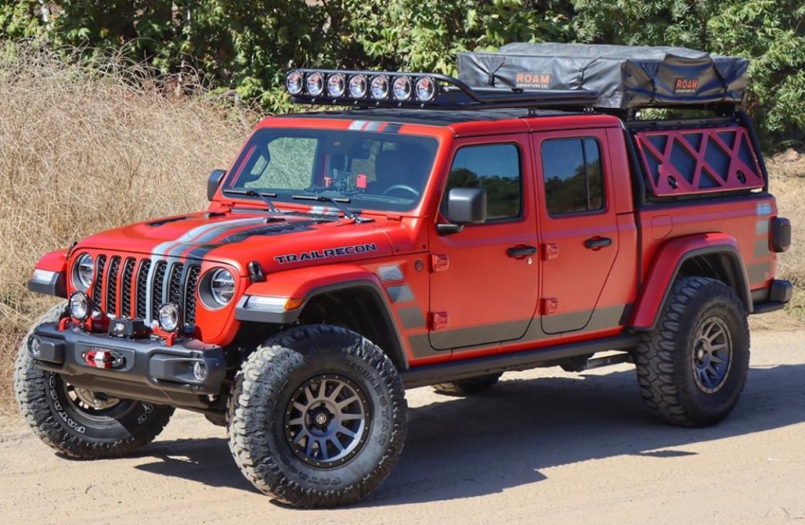 A red Jeep Gladiator parked on a dirt road