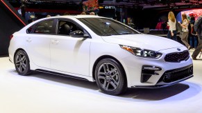 A white Kia Forte on display at an auto show