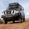 A black, lifted, 4x4, full-size van sits on a dirt road