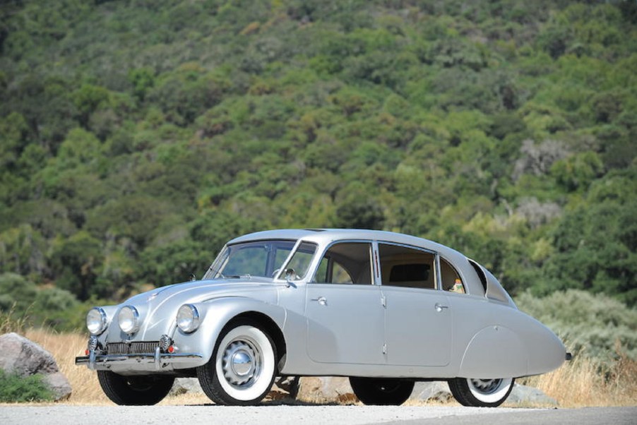 A silver 1941 Tatra T87 in front of a grassy hill