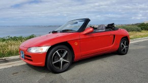 Red 1991 Honda Beat viewed from the side with the roof down