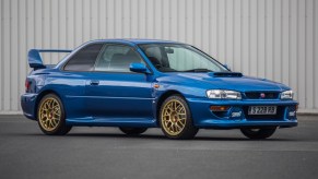 Blue 1998 Subaru Impreza 22B STi in front of a gray metal wall